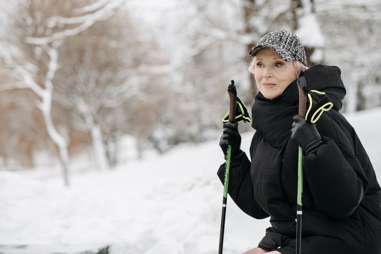 Senior woman enjoying a winter hike with trekking poles in a snowy landscape.